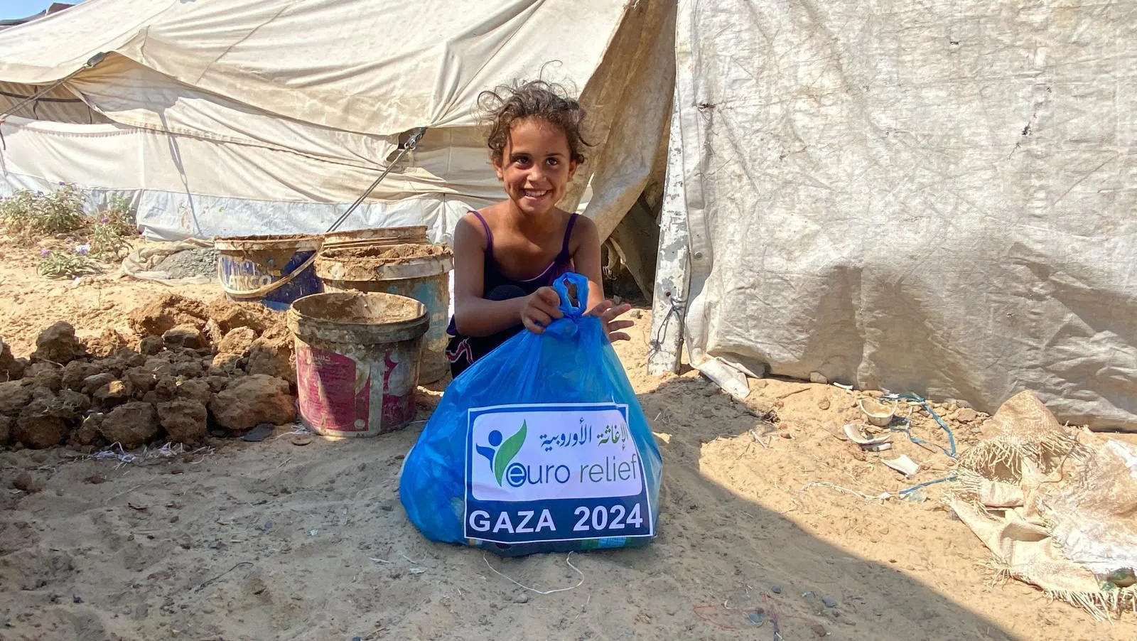 Children carry aid parcels through a displacement camp in Gaza